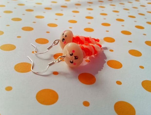 Pair of handmade polymer clay ghost earrings on a polka dot background